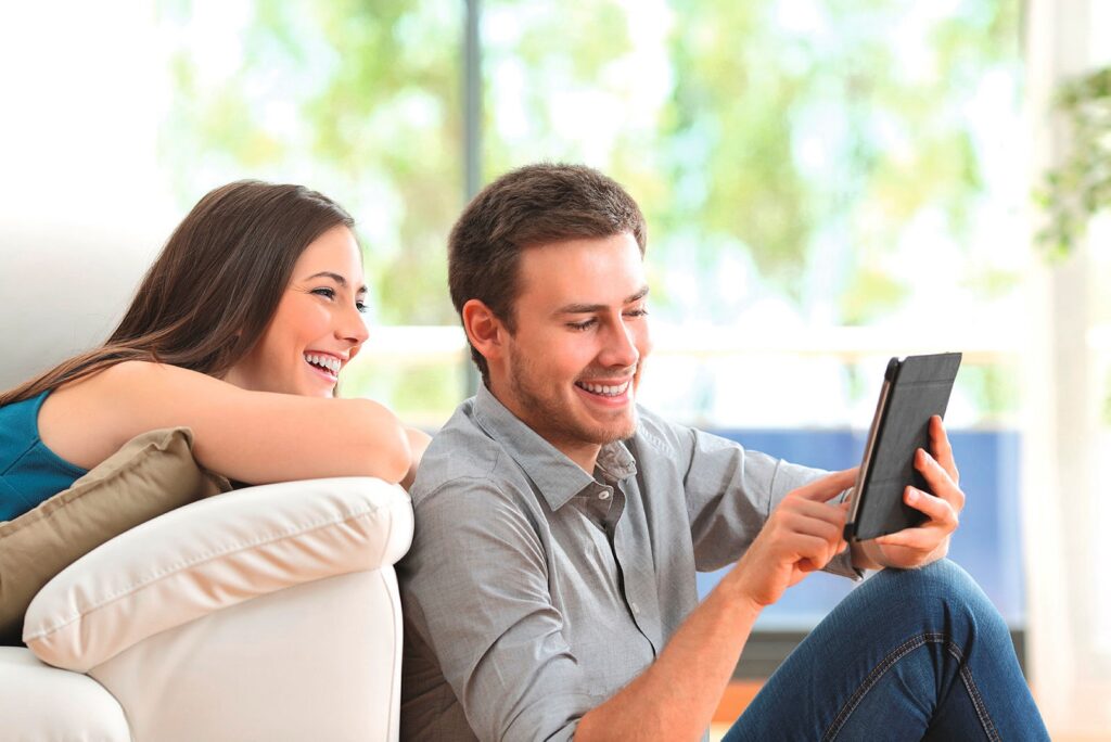 junges Paar interagiert mit Smarthome am Tablett