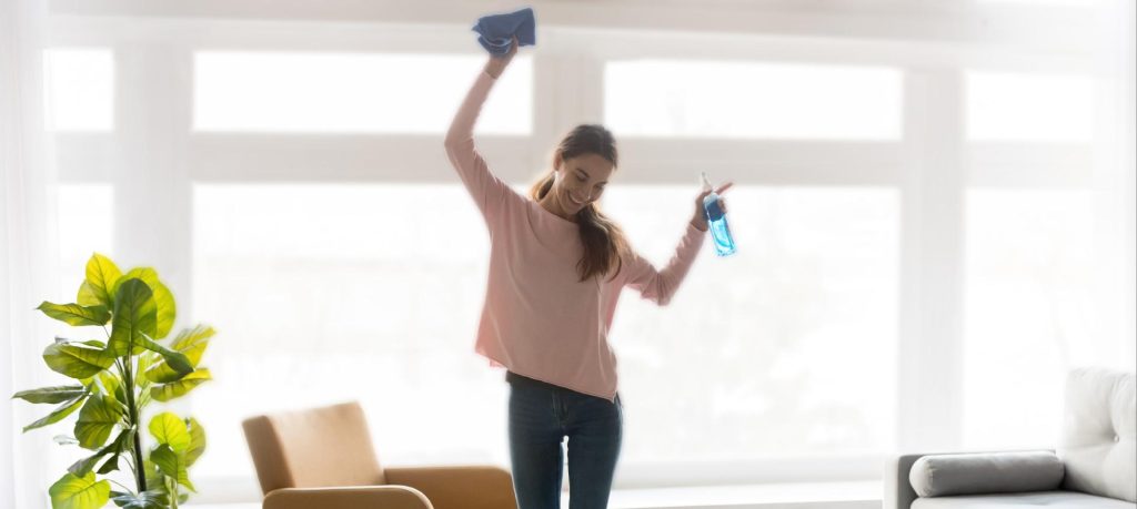 Frau tanzt beim Fensterputzen