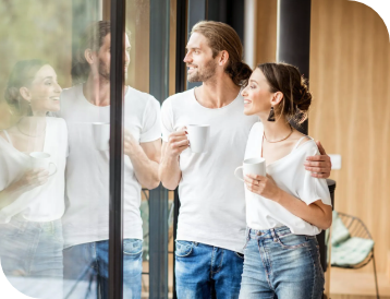 junges Paar steht am Fenster und trinkt Kaffee