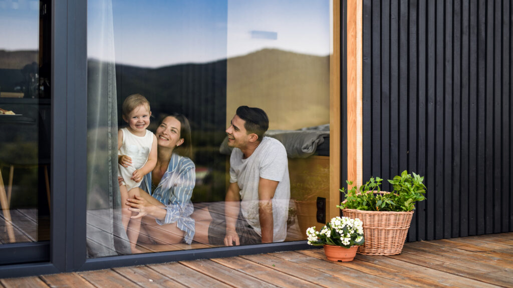 junge Familie sitzt vor bodentiefem Fenster