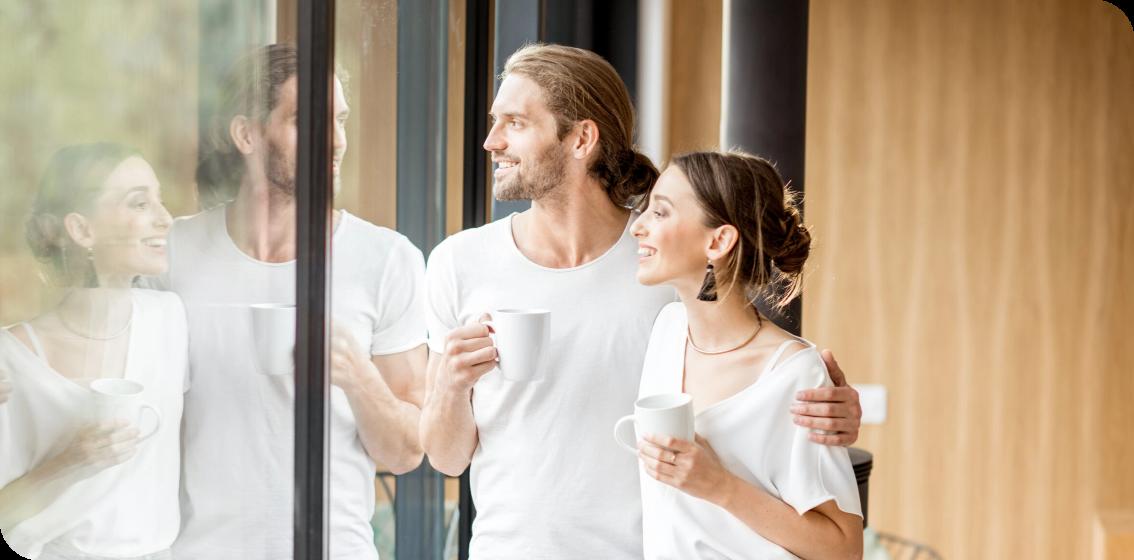 junges Paar sieht aus dem Fenster und trinkt Kaffee