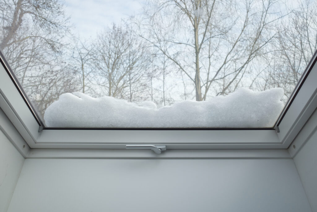 Schnee liegt auf einem Dachfenster